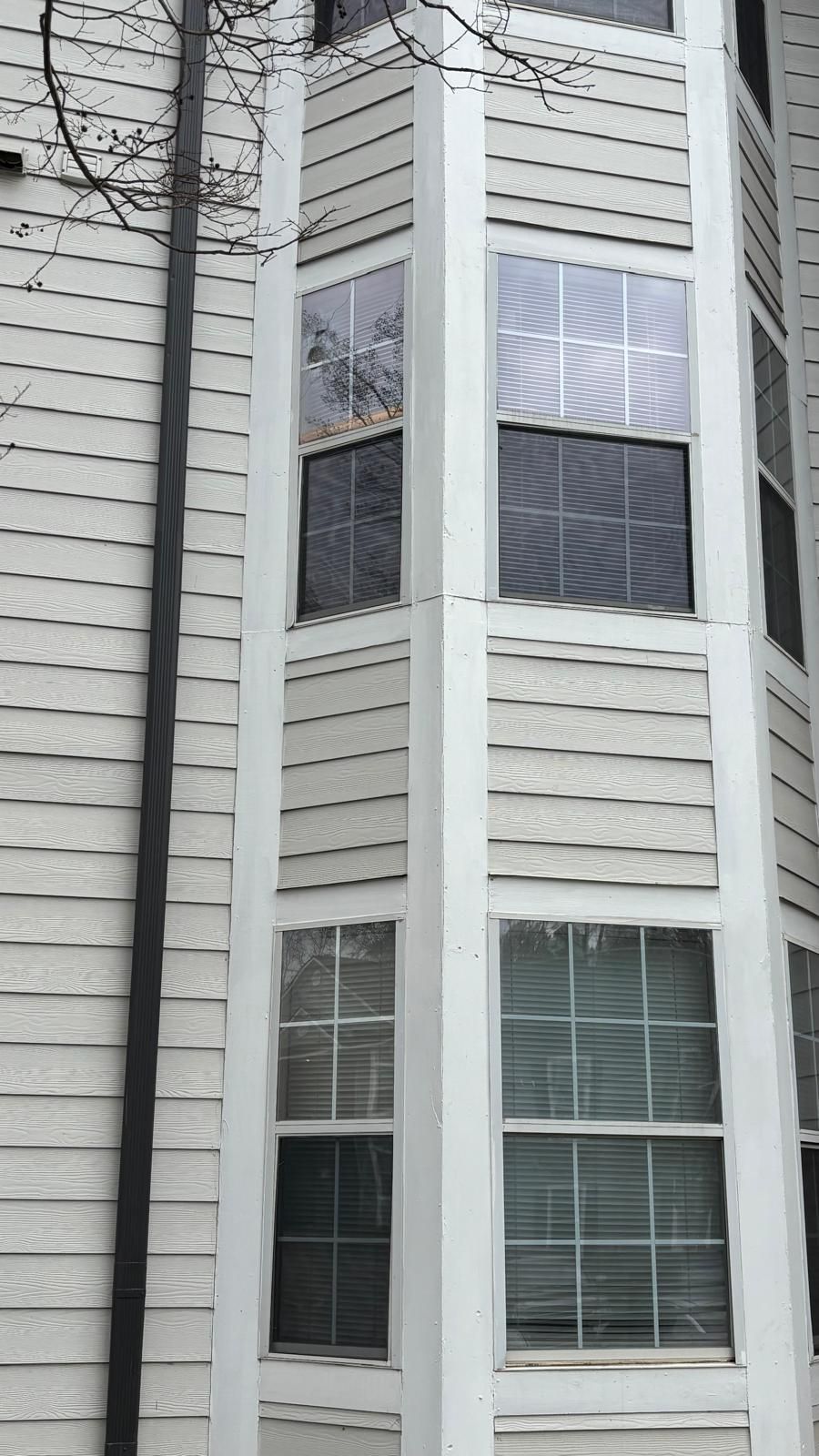 Exterior corner of a white house with bay windows and horizontal siding