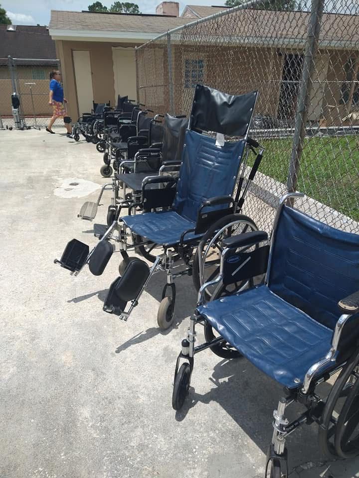 Row of blue and black wheelchairs lined up outside a building on a sunny sidewalk