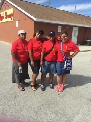 Four people in red shirts standing outside a building, smiling and posing together.