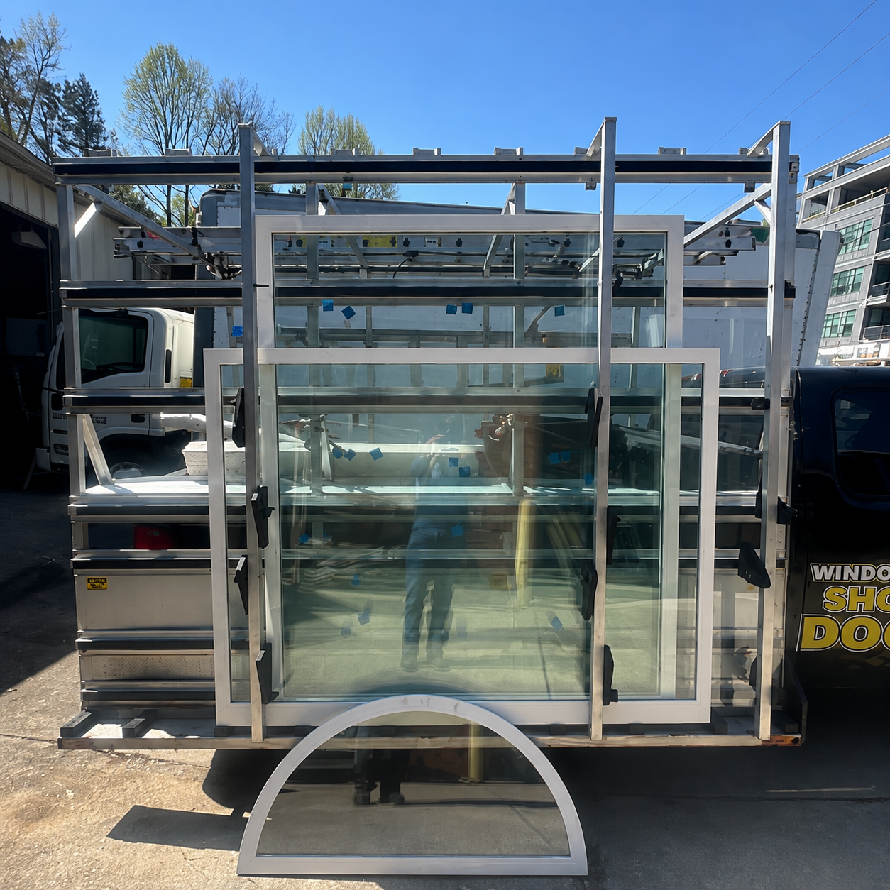 Glass-fronted metal rack or trailer parked outdoors under a blue sky.