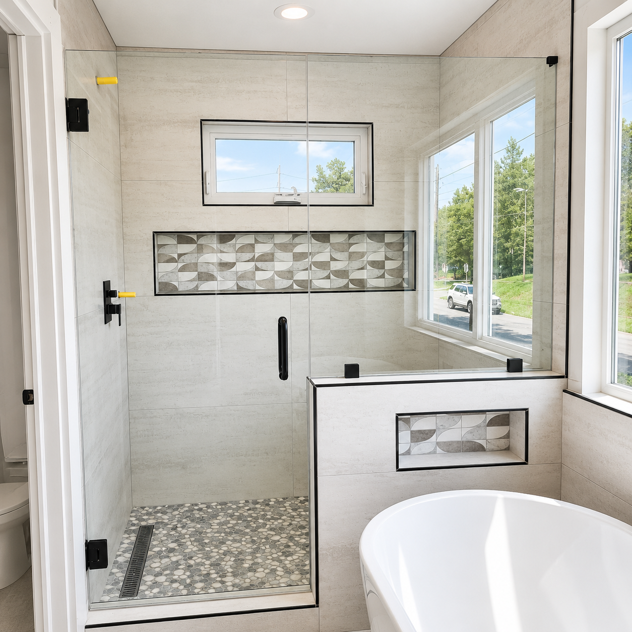 Modern tiled walk-in shower with mosaic accent, window, bench, and partial bathtub in a bright bathroom