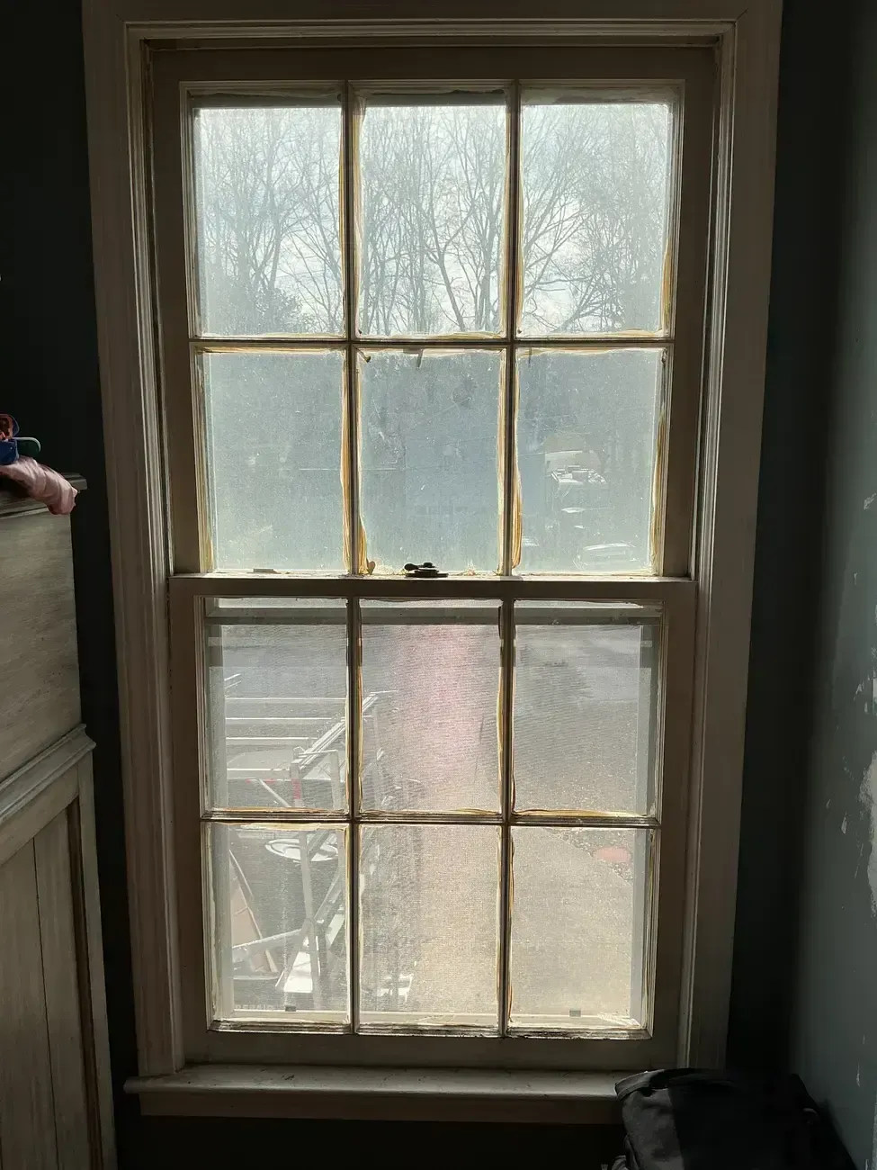 Old wooden window with six panes, looking out onto a foggy, leafless outdoor scene.