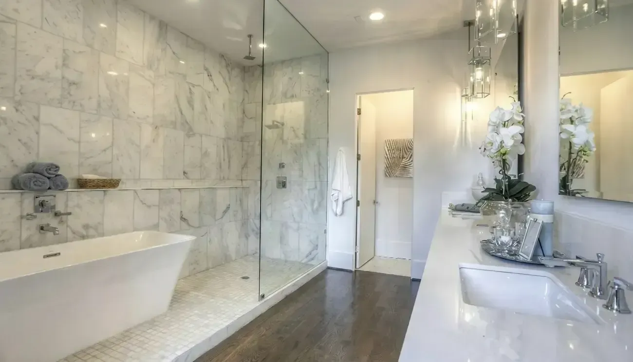 Luxurious marble bathroom with a freestanding tub, walk-in shower, vanity, and large mirror