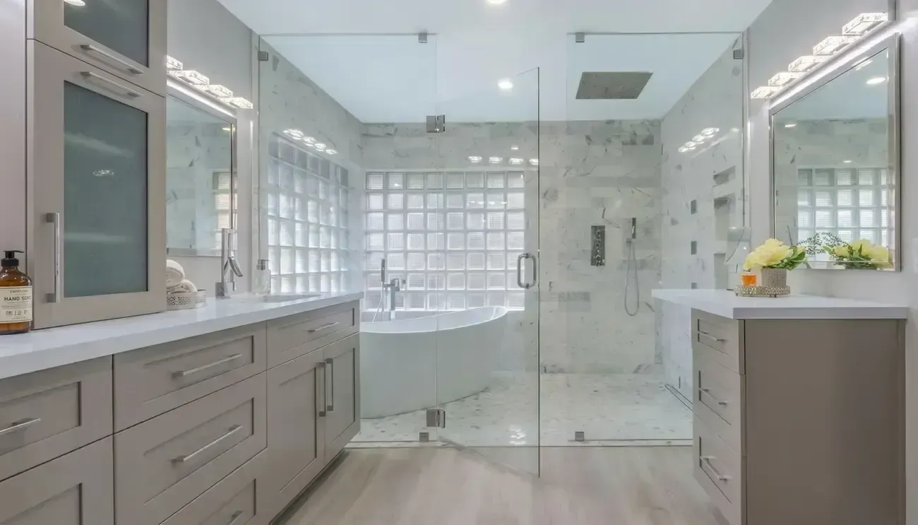 Bright modern bathroom with a glass-enclosed shower and soaking tub, white tile, and gray vanity cabinets