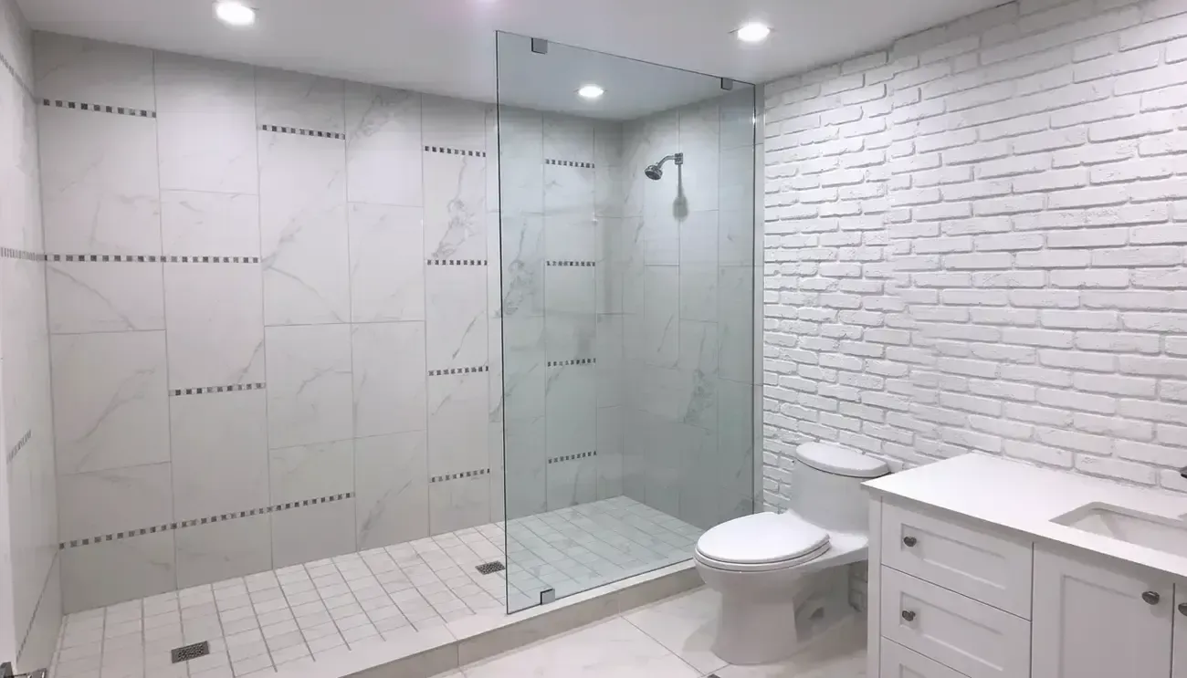 Modern white bathroom with glass shower, toilet, and vanity cabinet.