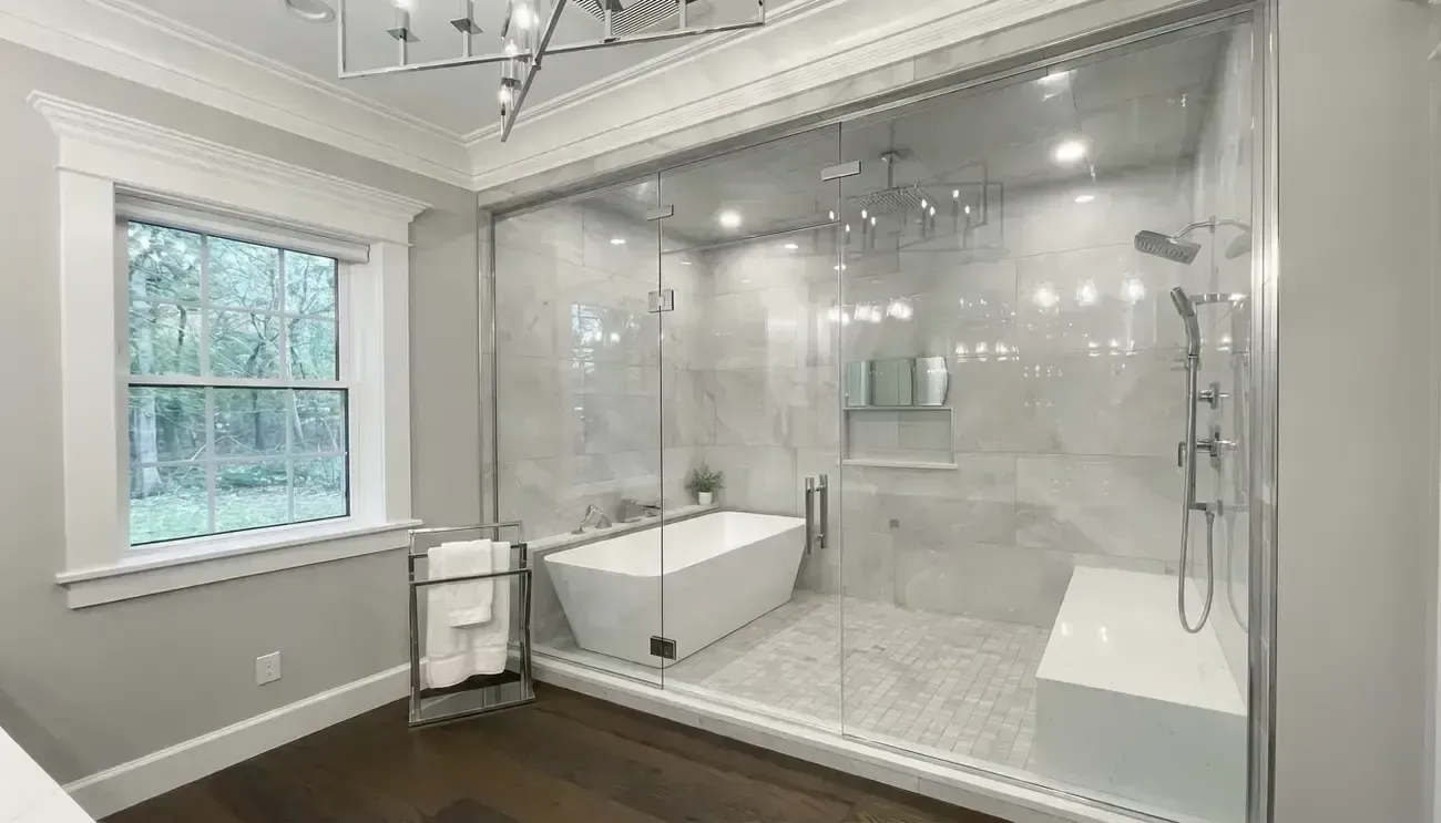Modern bathroom with glass shower enclosure, white freestanding tub, and dark wood floor beside a window