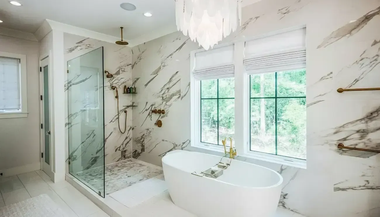 Bright modern bathroom with marble tile, glass shower, soaking tub, and two windows