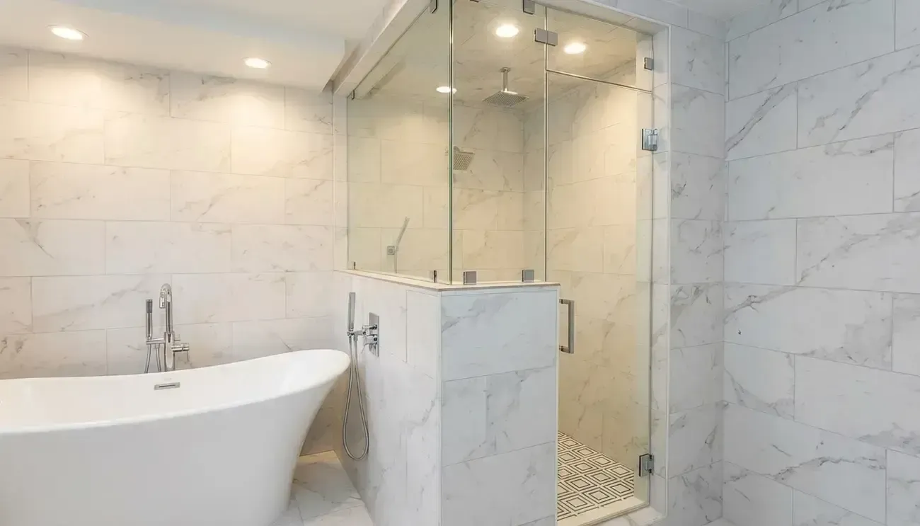 Modern white marble bathroom with freestanding tub, glass shower, and tiled walls