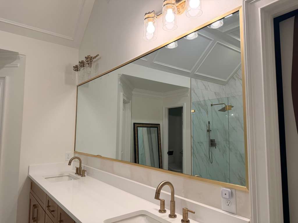 Bright bathroom vanity with double sinks, large mirror, and wall sconces