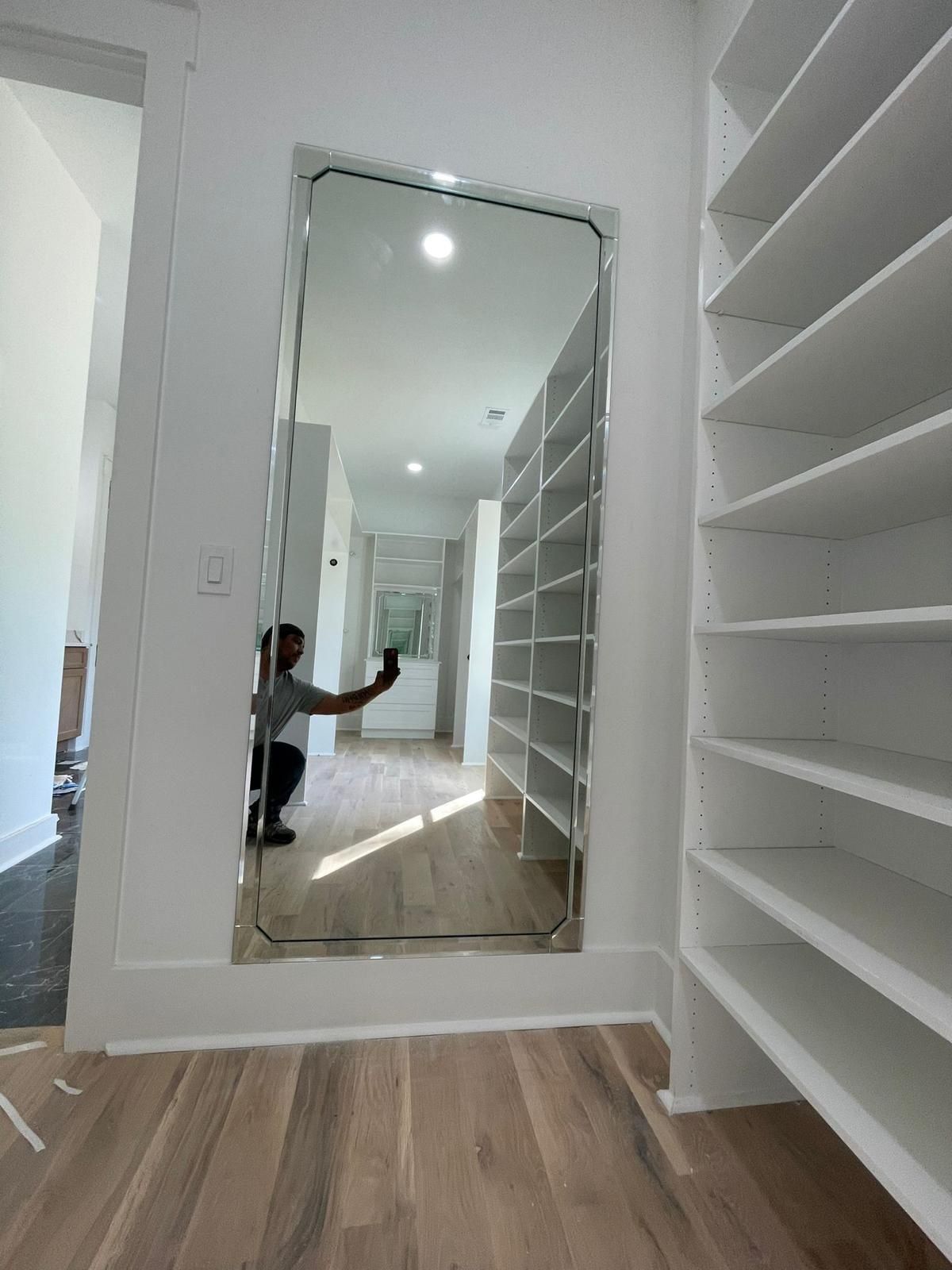 Walk-in closet with built-in shelves and a floor-length mirror reflecting a person taking the photo.