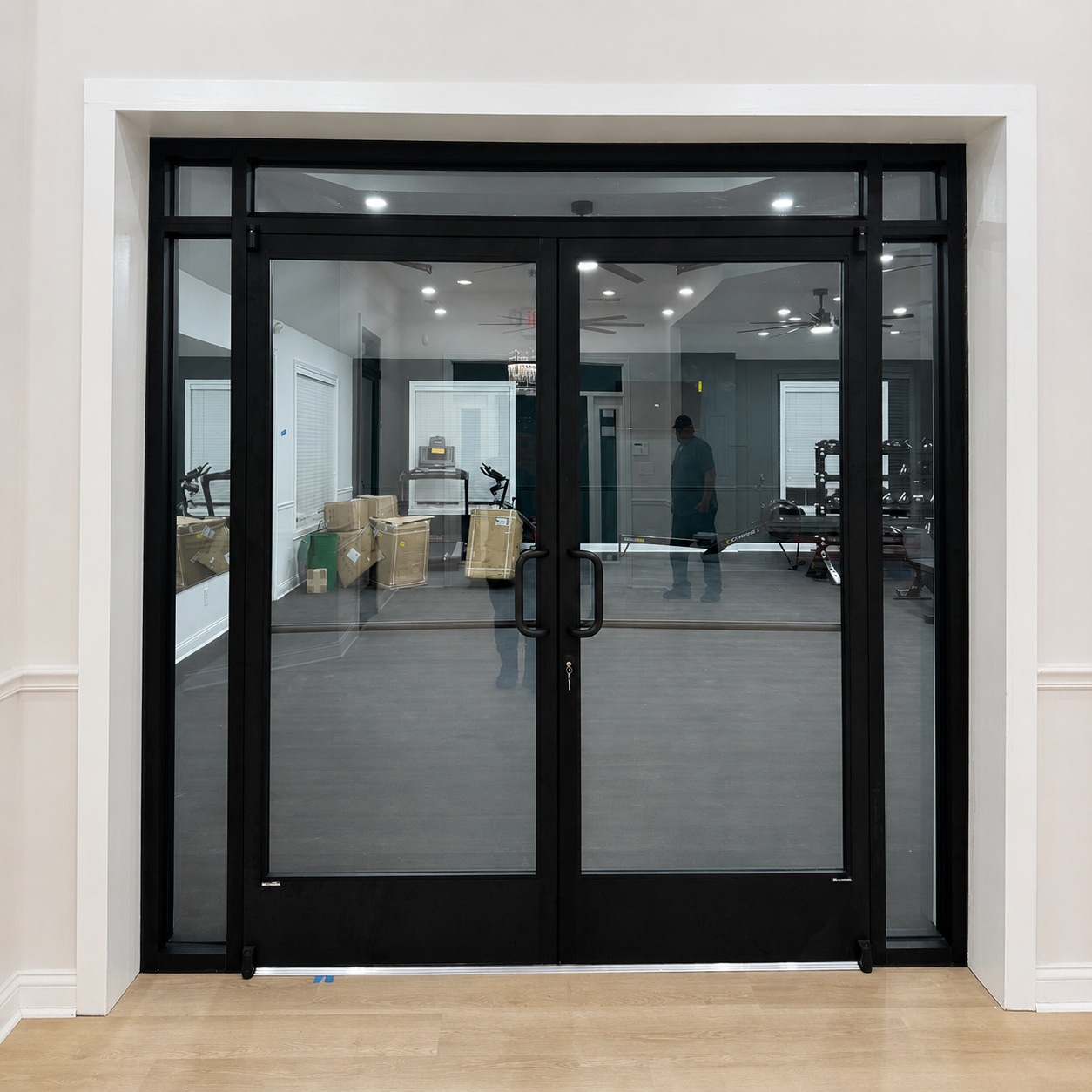 Black glass double doors with sidelights in a bright indoor lobby or storefront entrance
