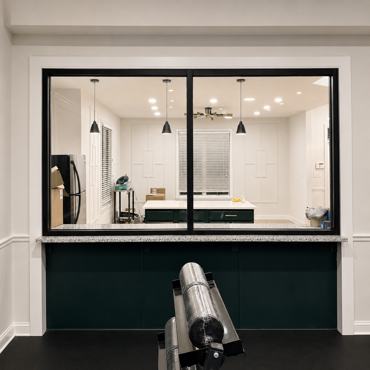 Modern kitchen pass-through window with white cabinets, dark island panel, and pendant lights