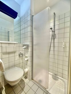 Ein Badezimmer mit Toilette, Dusche und Spiegel