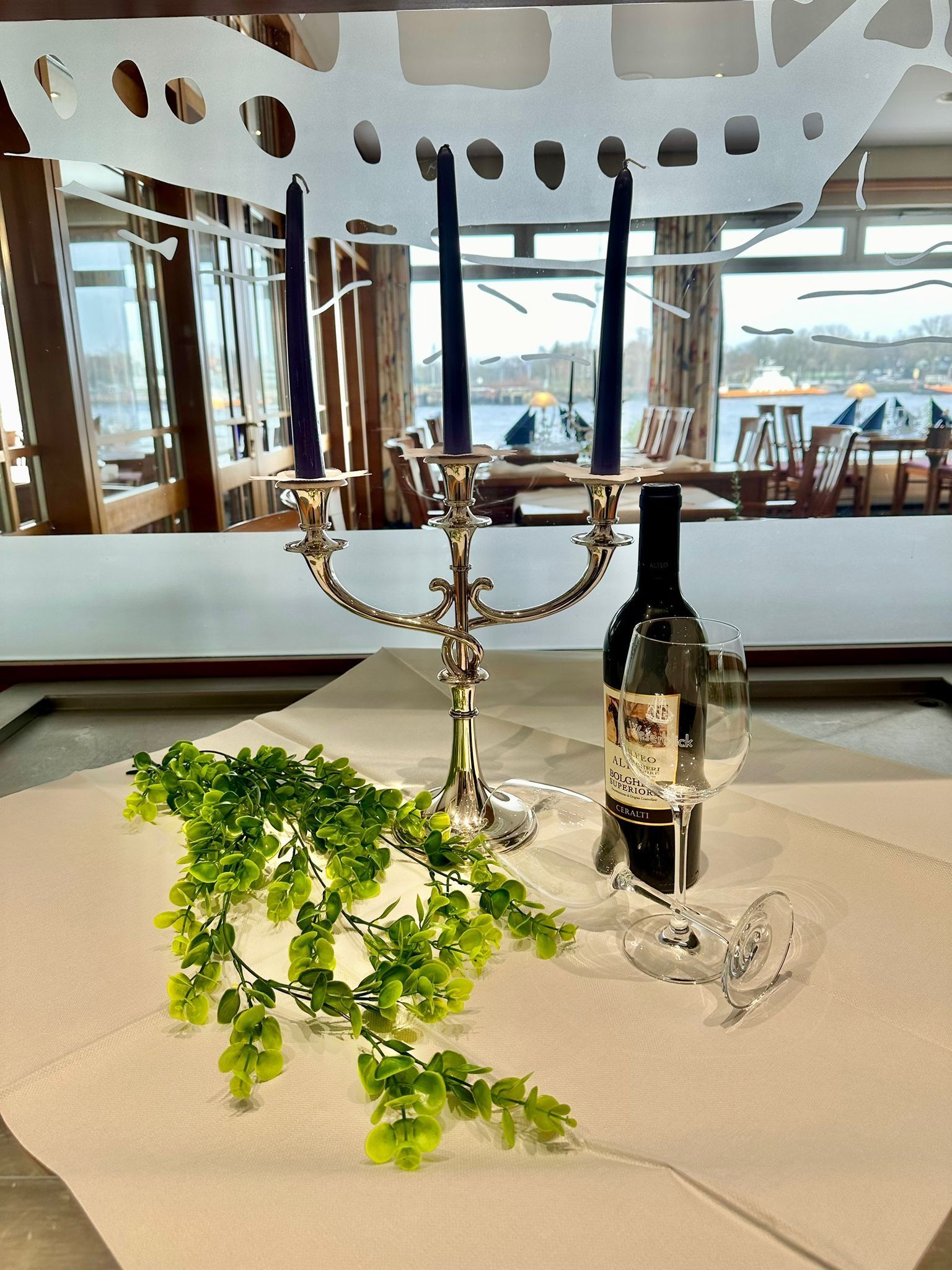 Eine Flasche Wein steht neben einem Kerzenständer auf einem Tisch.