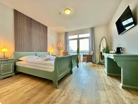 Ein Hotelzimmer mit Bett, Schreibtisch, Stühlen und Fernseher.