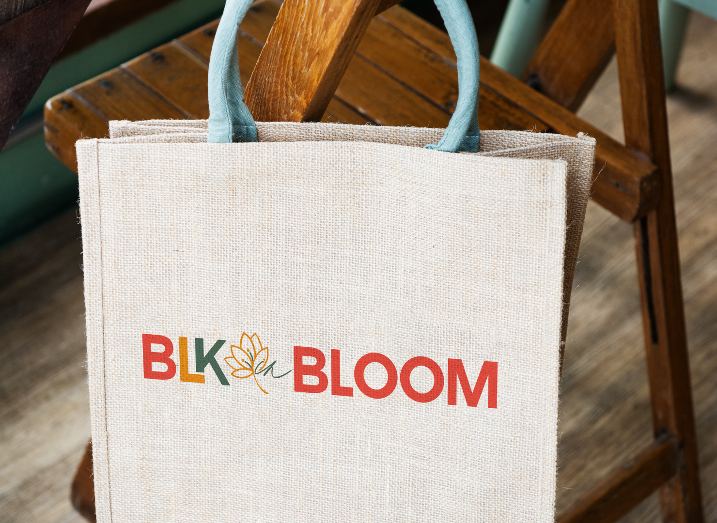 A white bag with the word bloom embroidered on it is sitting on a wooden chair.