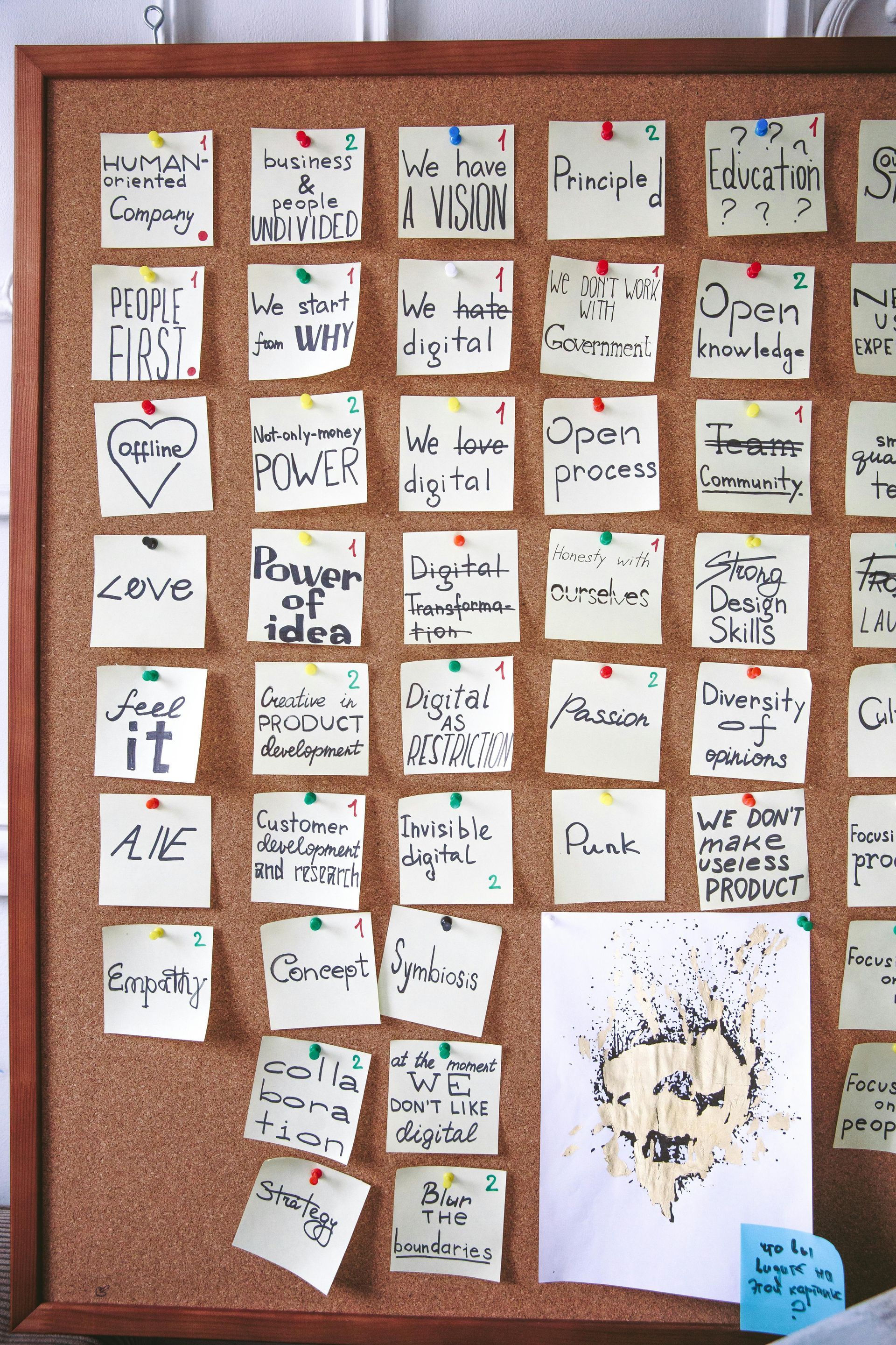 A cork board with sticky notes on it including one that says