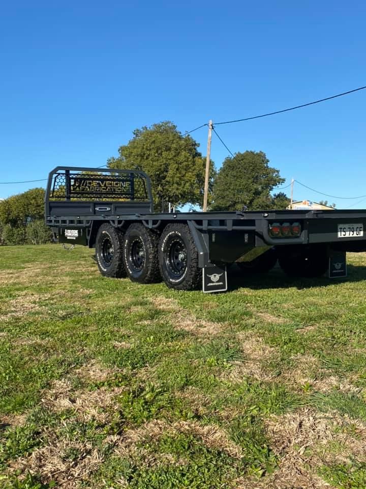 A Flatbed Truck is Parked in a Grassy Field — Deveigne Fabrications In Brocklehurst, NSW