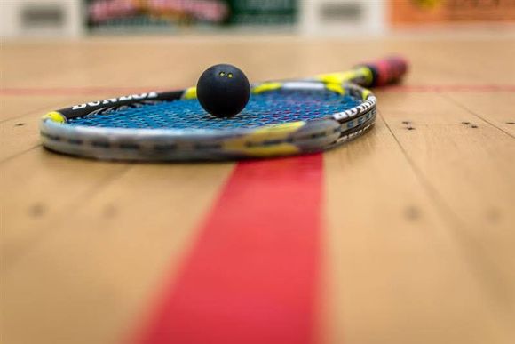 Table tennis paddle with ball resting on a wooden court, red line in the foreground