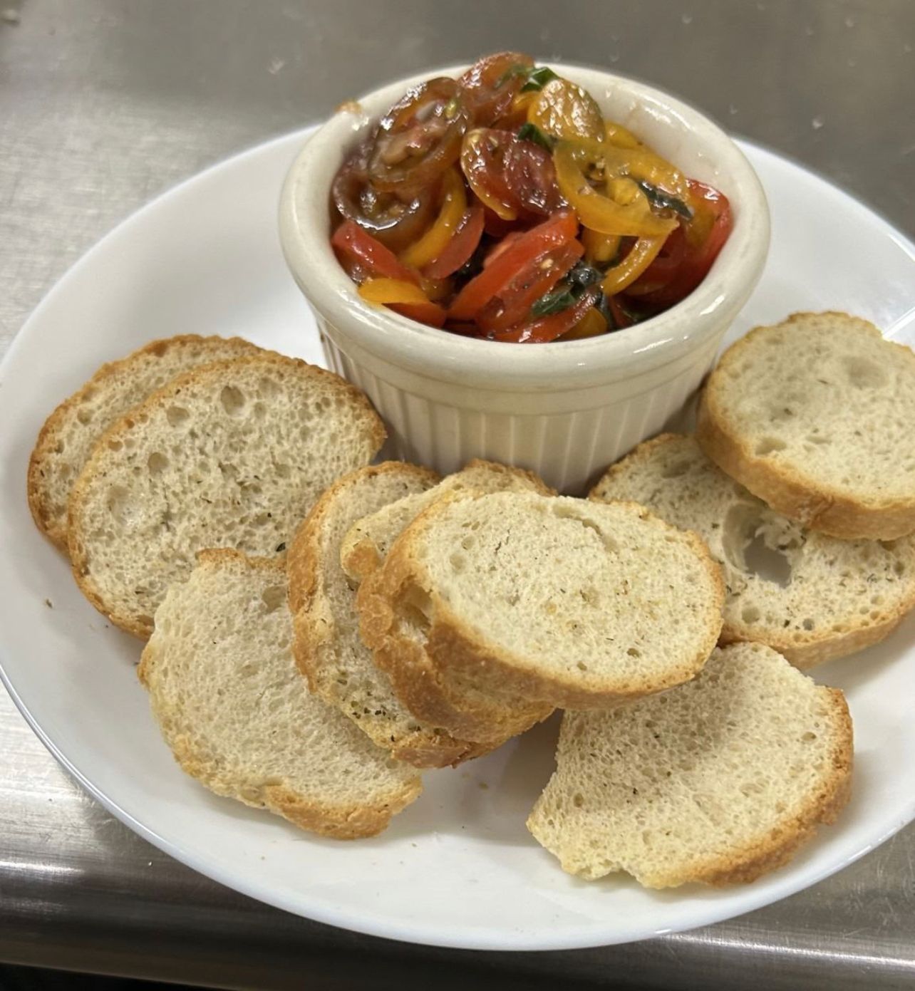 A white plate topped with bread and a bowl of vegetables