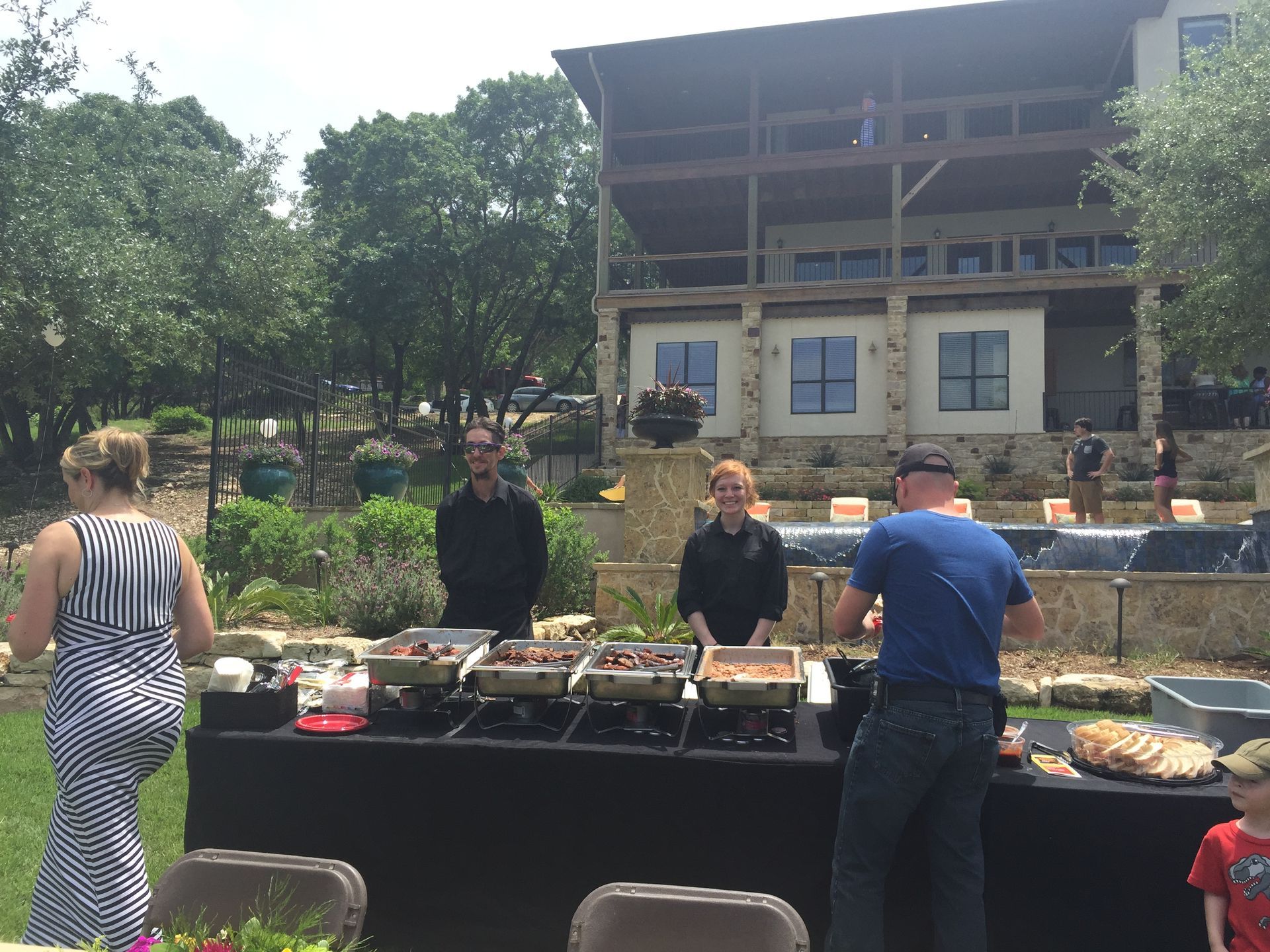 A group of people standing around a buffet table in front of a large building