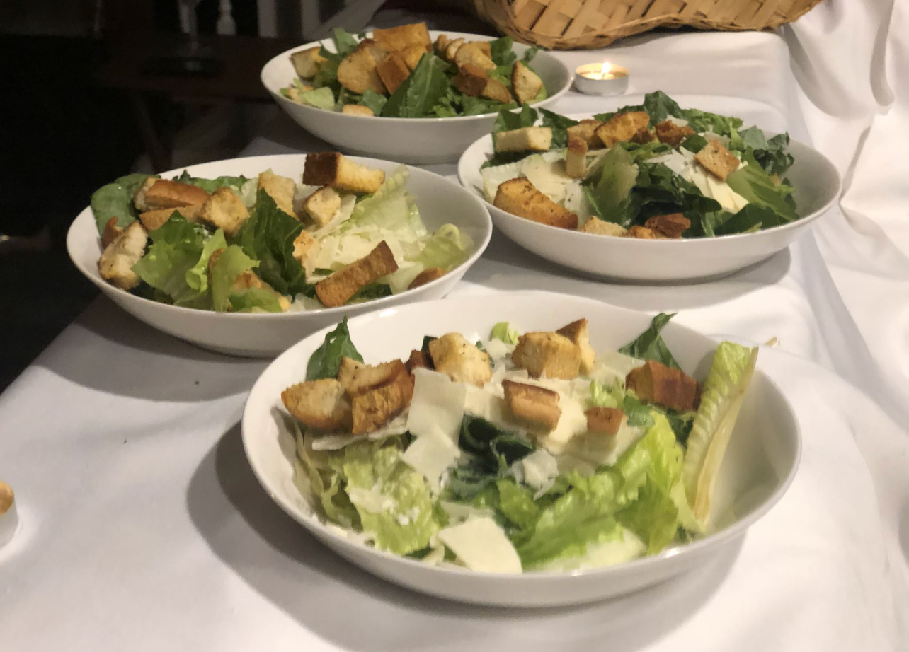 Three bowls of caesar salad are on a table.