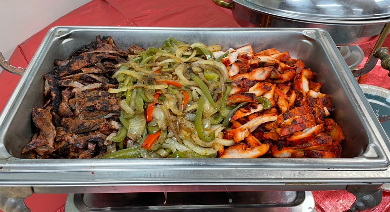A buffet tray filled with meat and vegetables on a table.