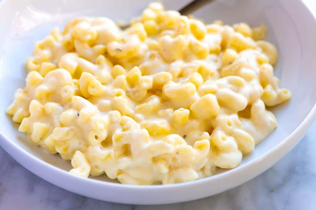 A bowl of macaroni and cheese with a spoon in it.