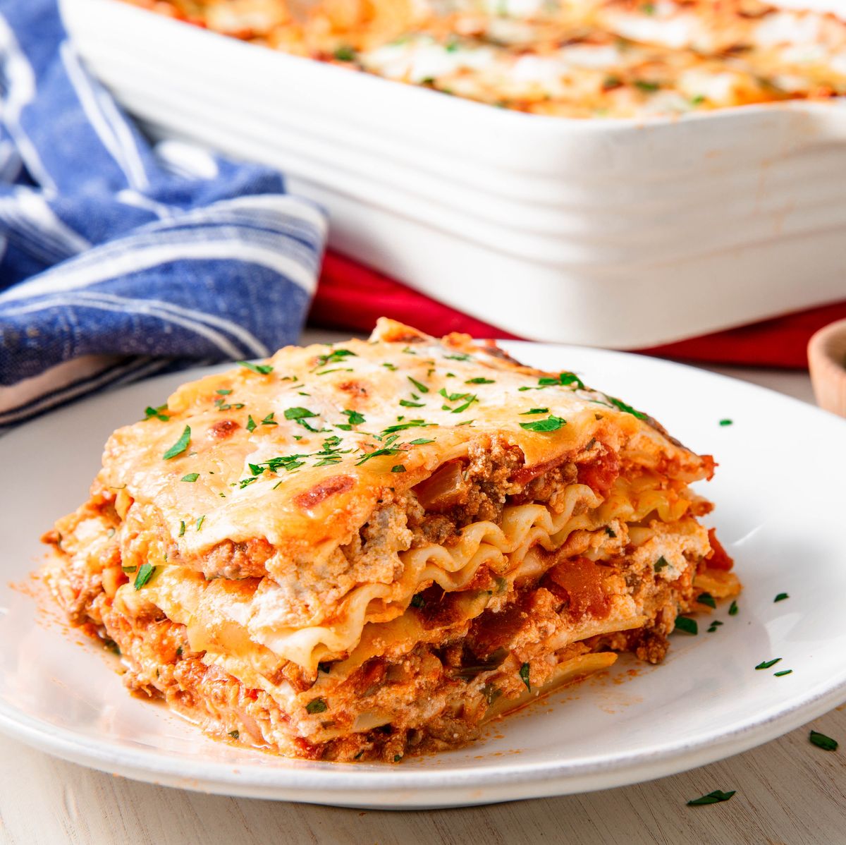 A slice of lasagna is on a white plate.