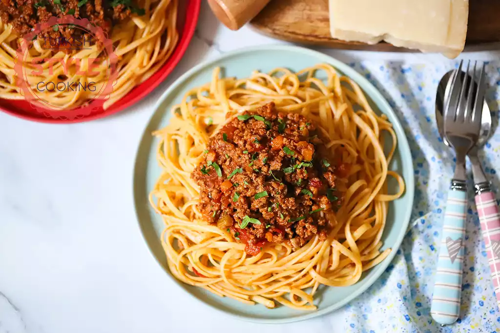 A plate of spaghetti with meat sauce and a fork on a table.