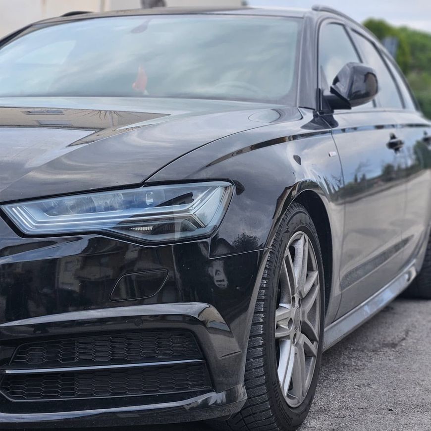 Berlina Audi nera parcheggiata in strada, vista frontale sinistra con carrozzeria lucida e cerchi in lega.