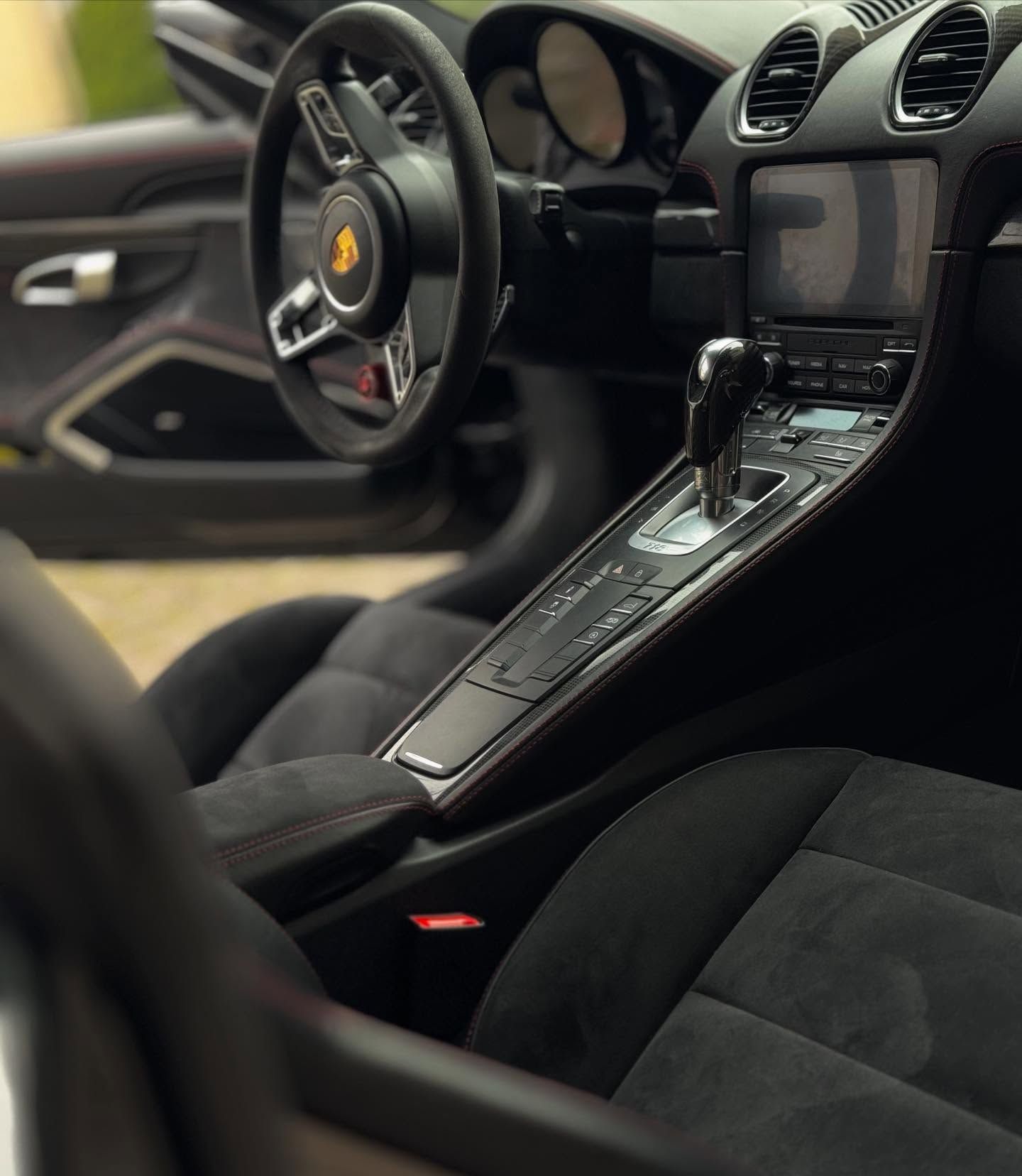 Interni di lusso per auto sportiva con sedili, volante e console centrale in pelle nera.