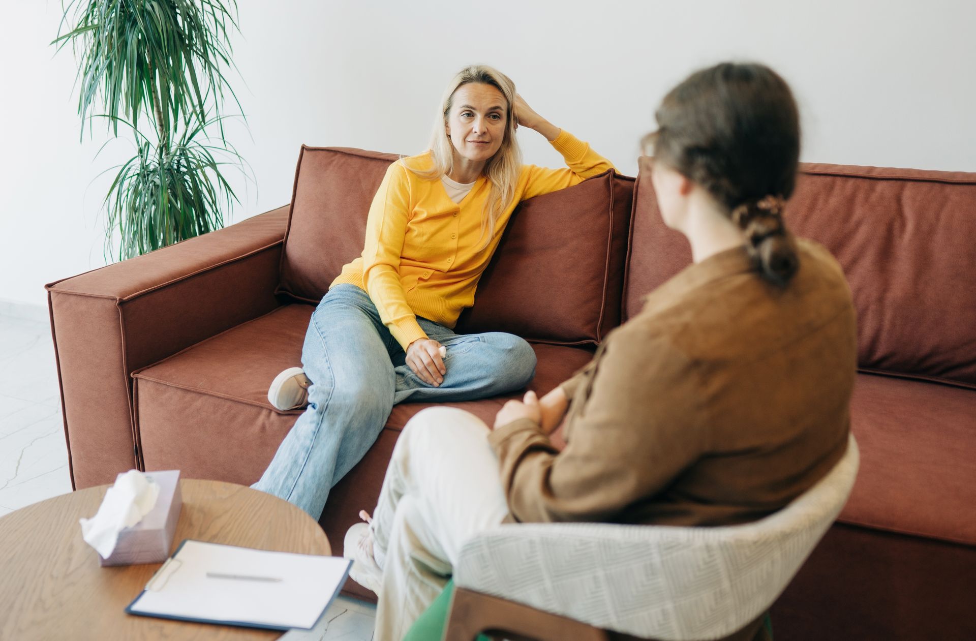 Therapist and client talking in a living room, with the client holding a phone and gesturing.