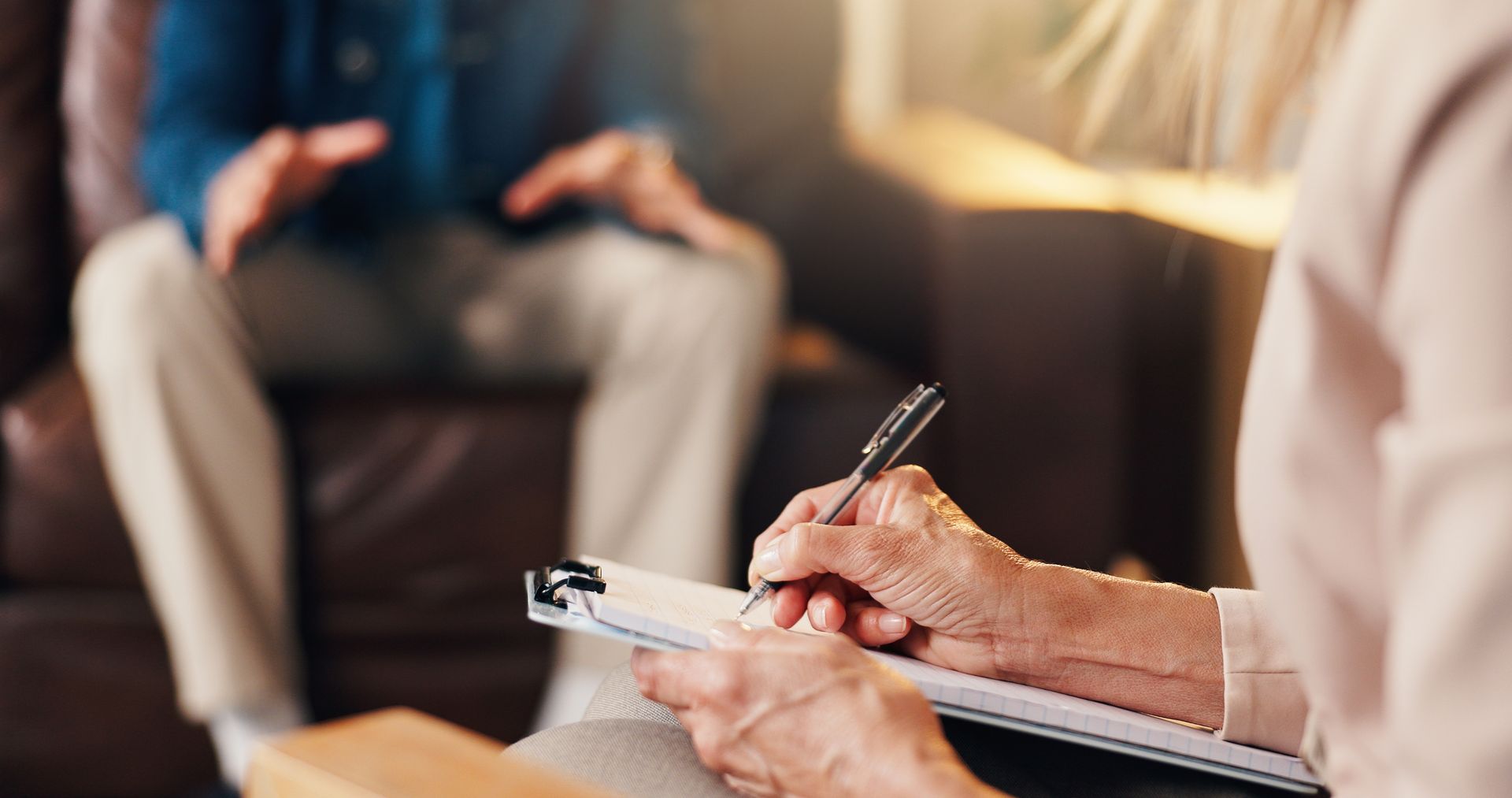 Therapist and client talking in a living room, with the client holding a phone and gesturing.