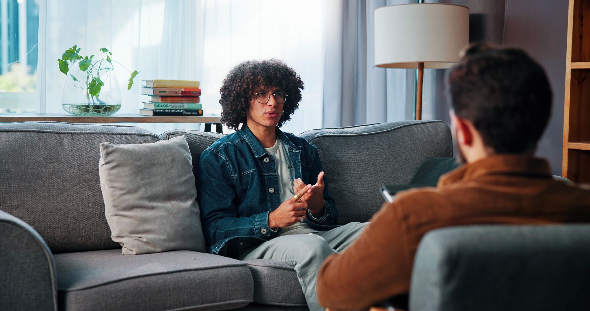 Therapist and client talking in a living room, with the client holding a phone and gesturing.
