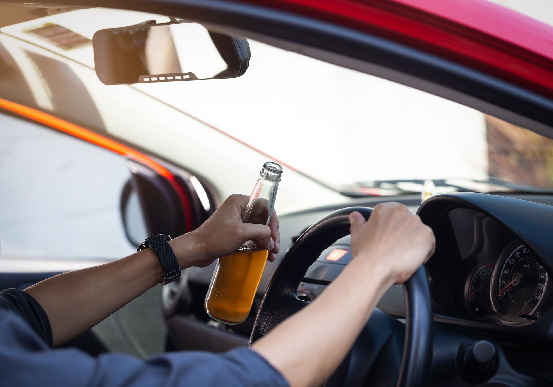 Driver holding beer bottle while steering a car
