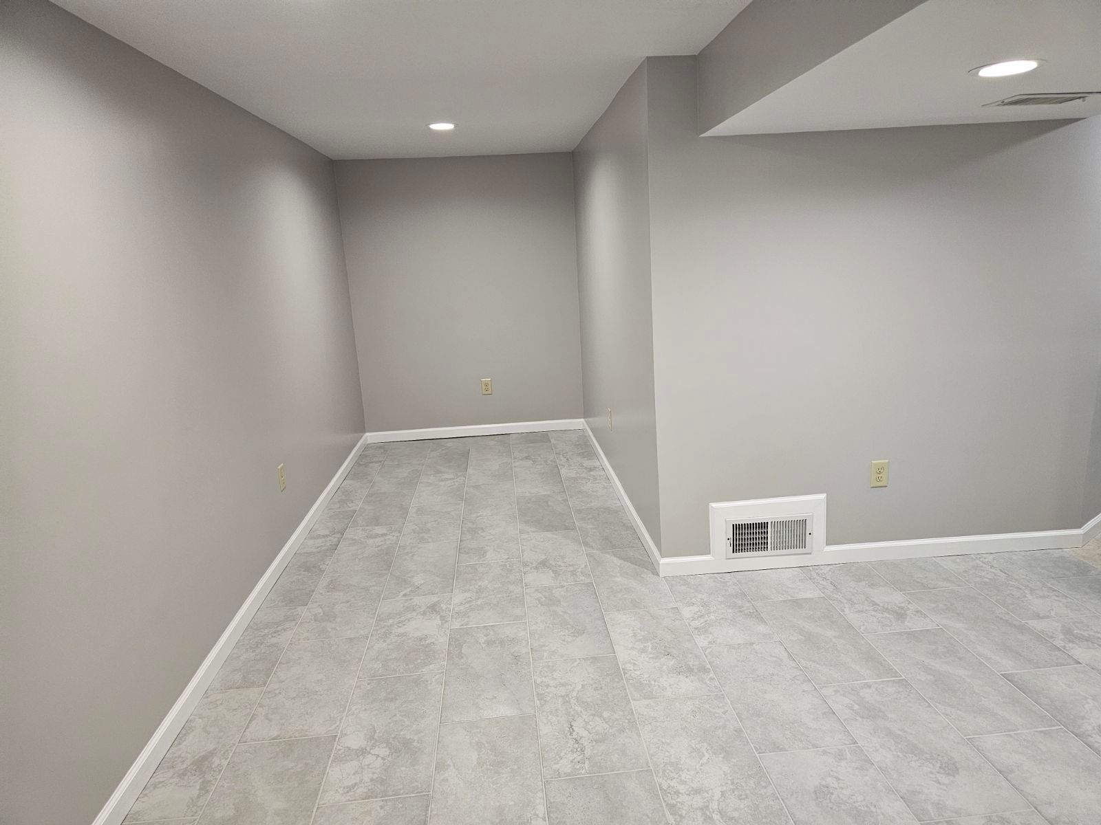 An empty basement with gray walls and a gray carpet.