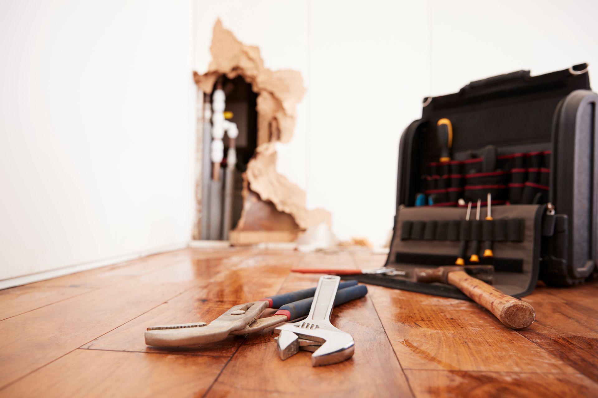 Water damage scene with tools: damaged wall, flooded floor, and open toolbox with tools.