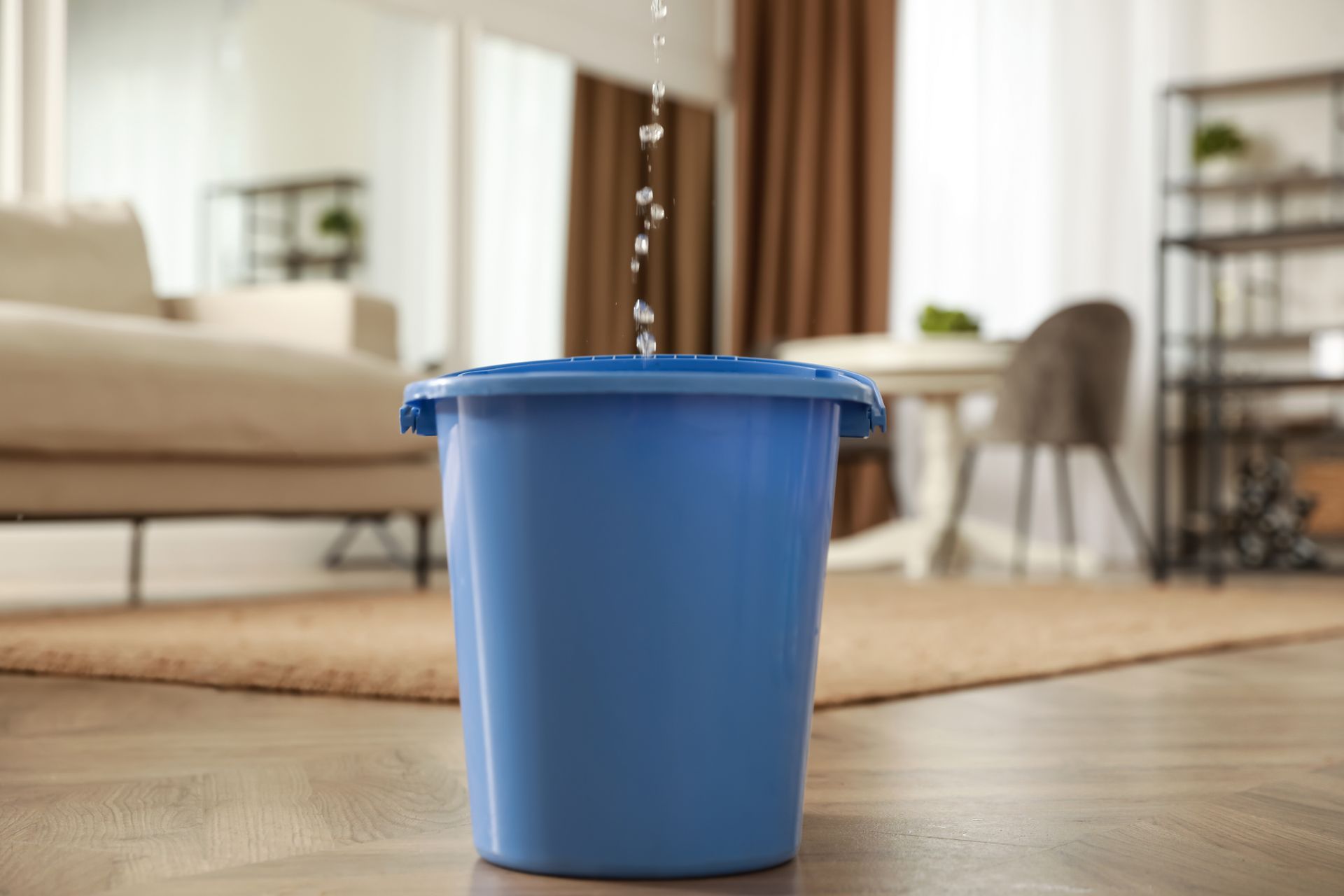 Blue bucket on a wooden floor in a bright living room