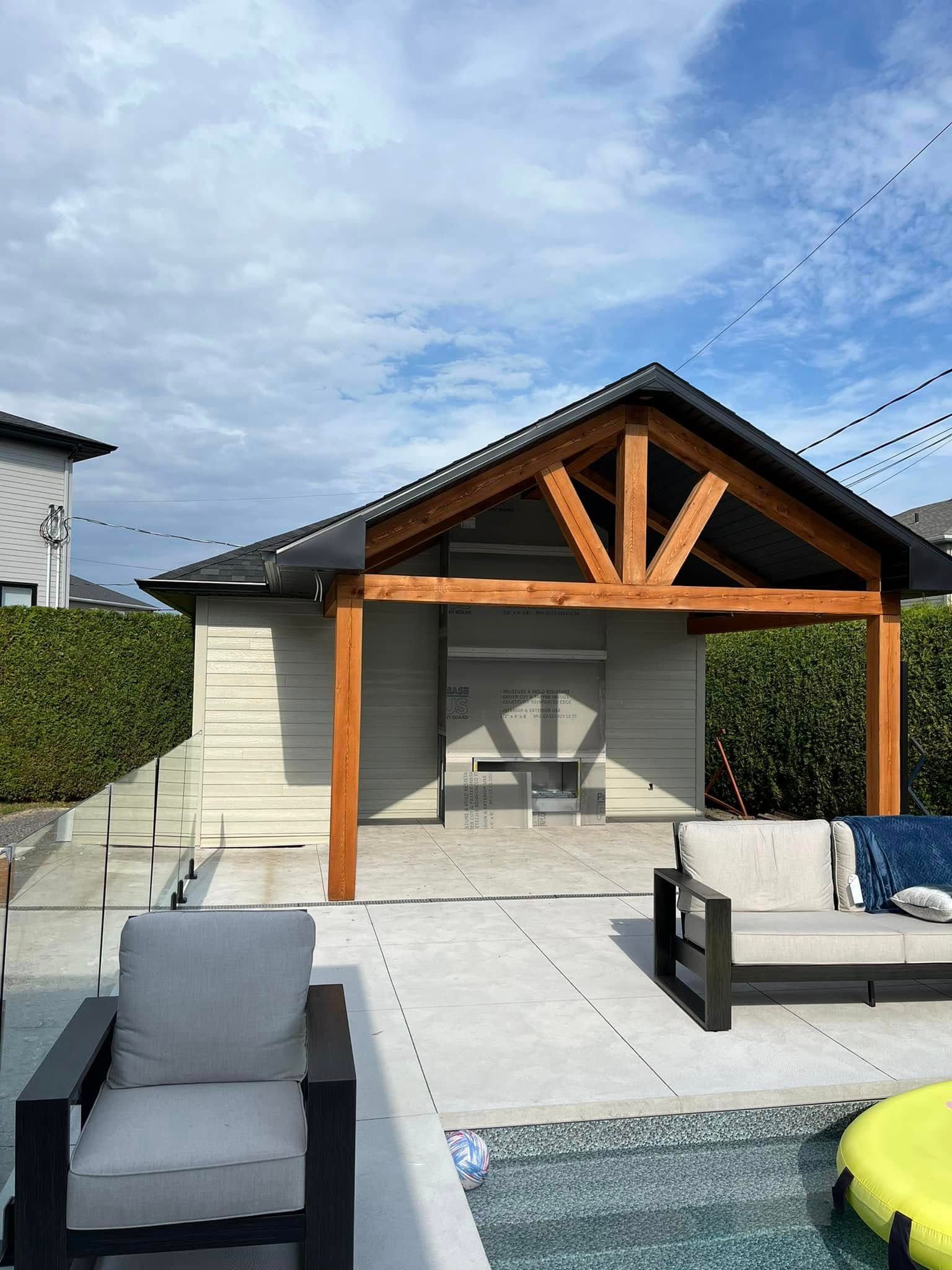 Cabane de piscine avec poutres en bois, bardage gris et sièges extérieurs.