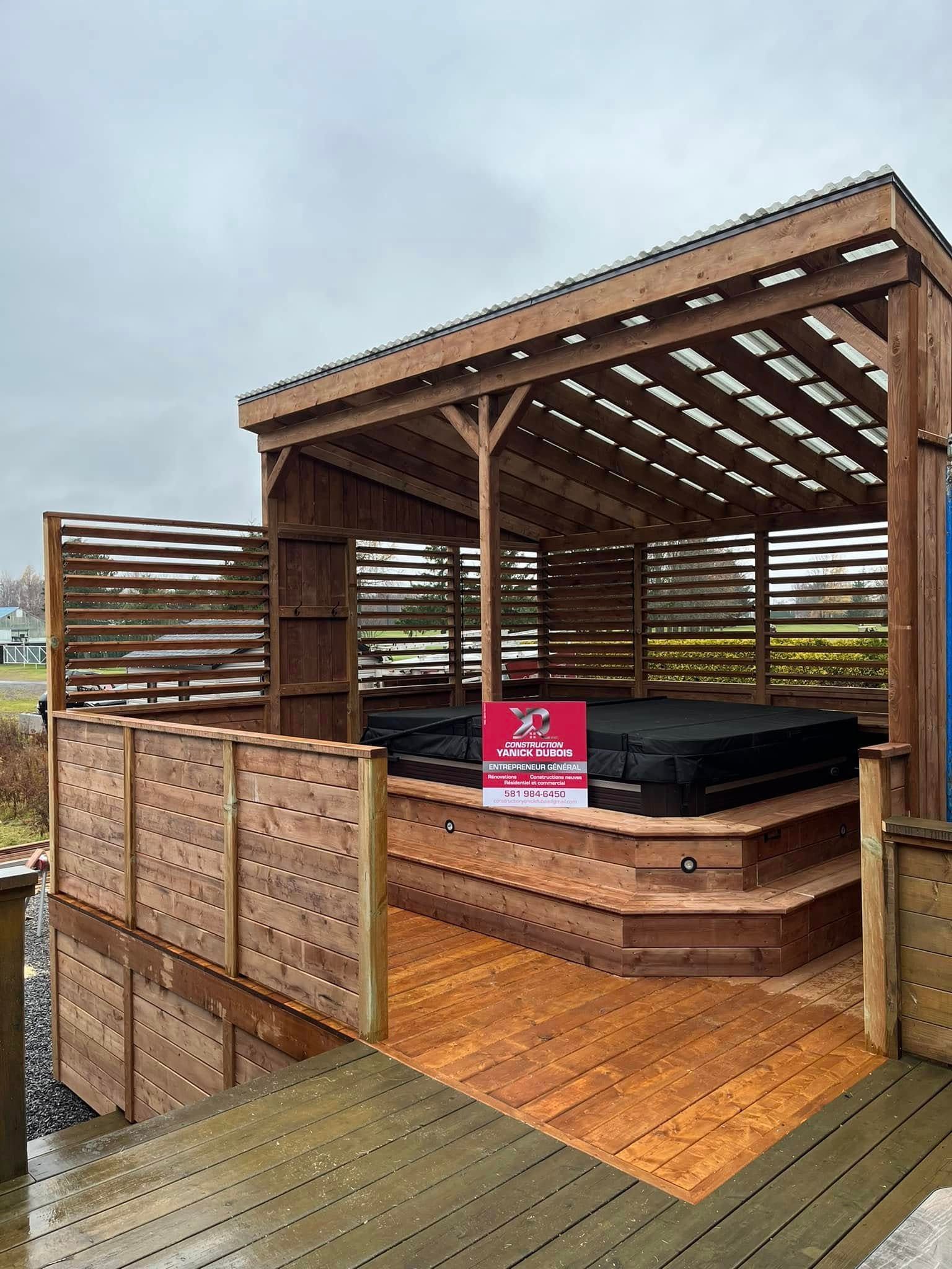 Abri pour jacuzzi en bois avec marches, toit en pergola et parois à claire-voie.