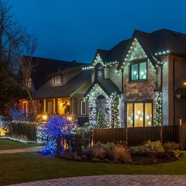 Houses decorated with Christmas lights at night, blue and white lights shining.