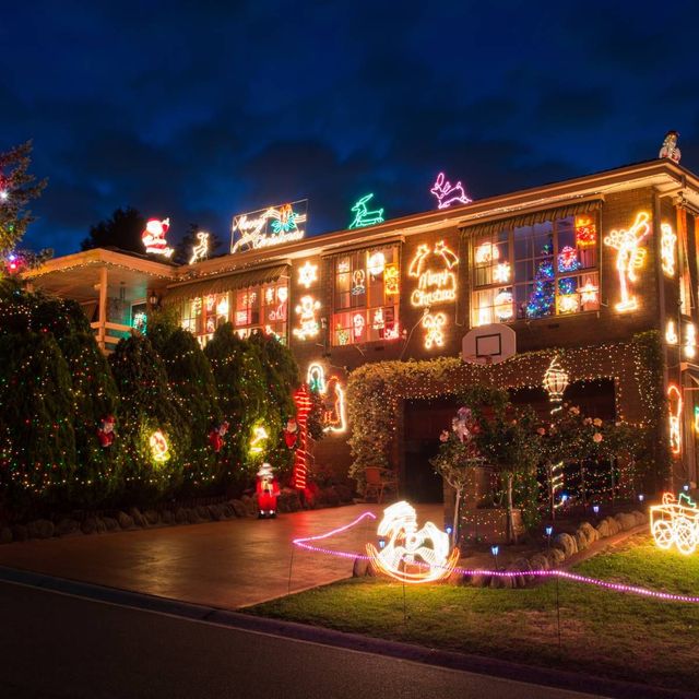 House covered in Christmas lights, with illuminated displays in the windows and on the roof at night.