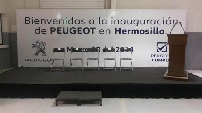 Un escenario montado con cinco sillas en fila, un atril y un gran cartel que daba la bienvenida a los invitados a la inauguración de Peugeot.
