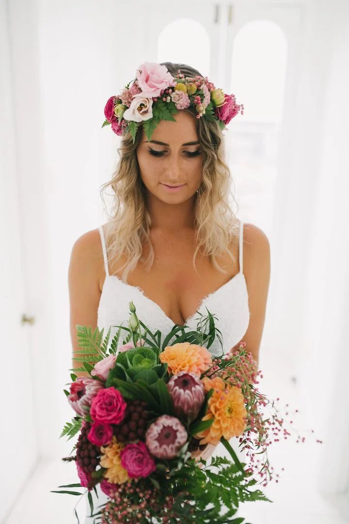 The bride is wearing a flower crown and holding a bouquet of flowers.