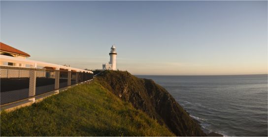 A lighthouse is sitting on top of a cliff overlooking the ocean.