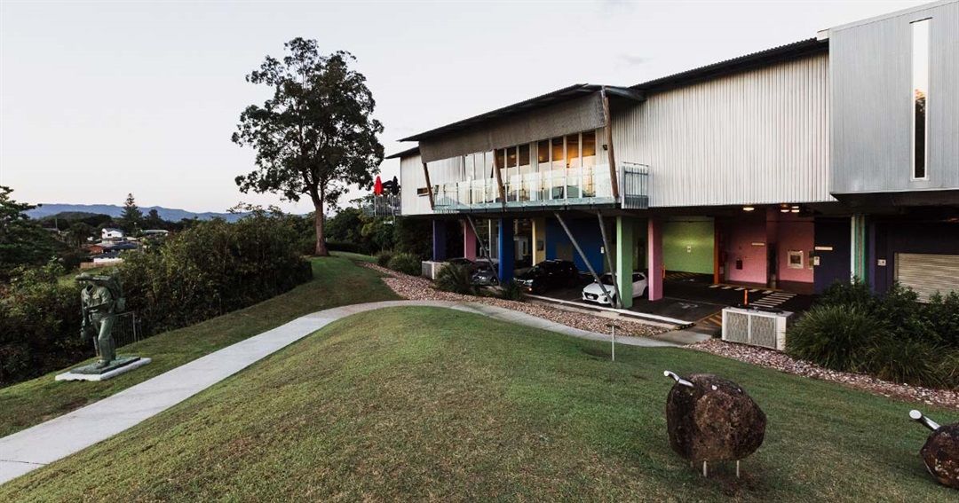 A sheep is standing in the grass in front of a building.