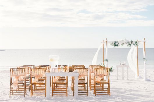 A row of chairs and a table on a beach.