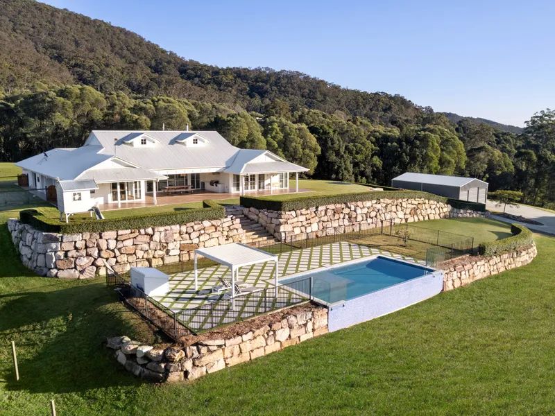 An aerial view of a house with a swimming pool in front of it.