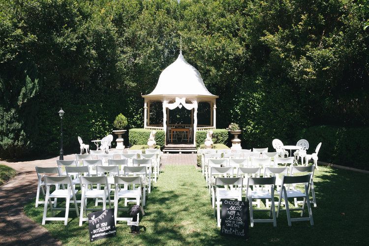 A wedding ceremony is taking place in front of a gazebo.